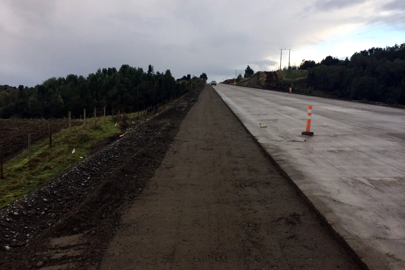La calzada de hormigón terminada corriendo recta hacia el horizonte, con su berma perfilada al costado
