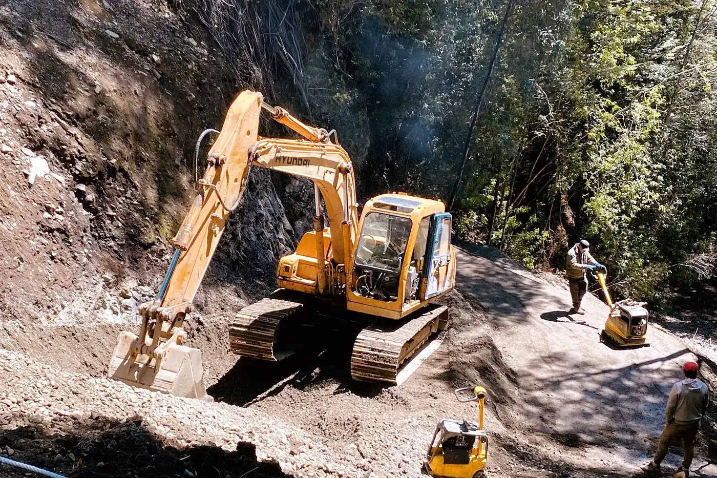 Excavadora trabajando el corte de un talud, con el brazo apoyado sobre el material