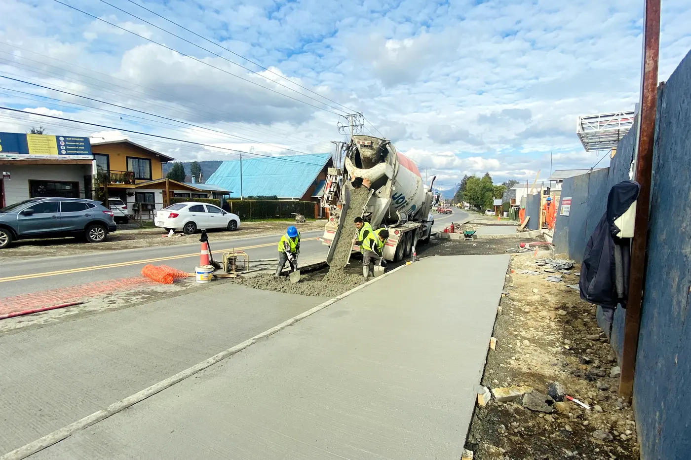 Camión mixer descargando hormigón sobre la calzada mientras la cuadrilla lo extiende