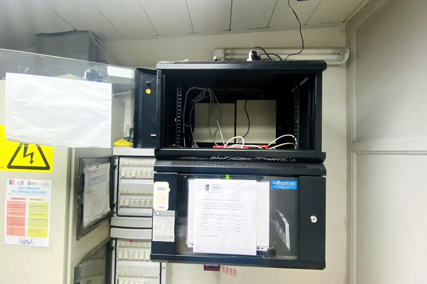 Tablero eléctrico y gabinete de equipos instalados en su sala, con la señalética de riesgo eléctrico