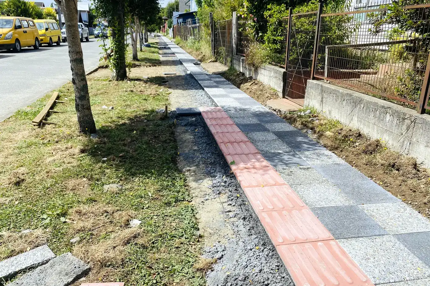 Vereda terminada con su franja de guía táctil, entre la calzada y el antejardín